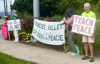 Protesters holding peace signs and banners outdoors